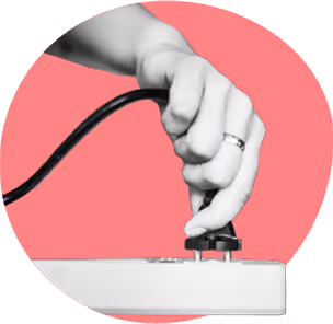 Hand plugging a black power cord into a white power strip against a pink circular background.